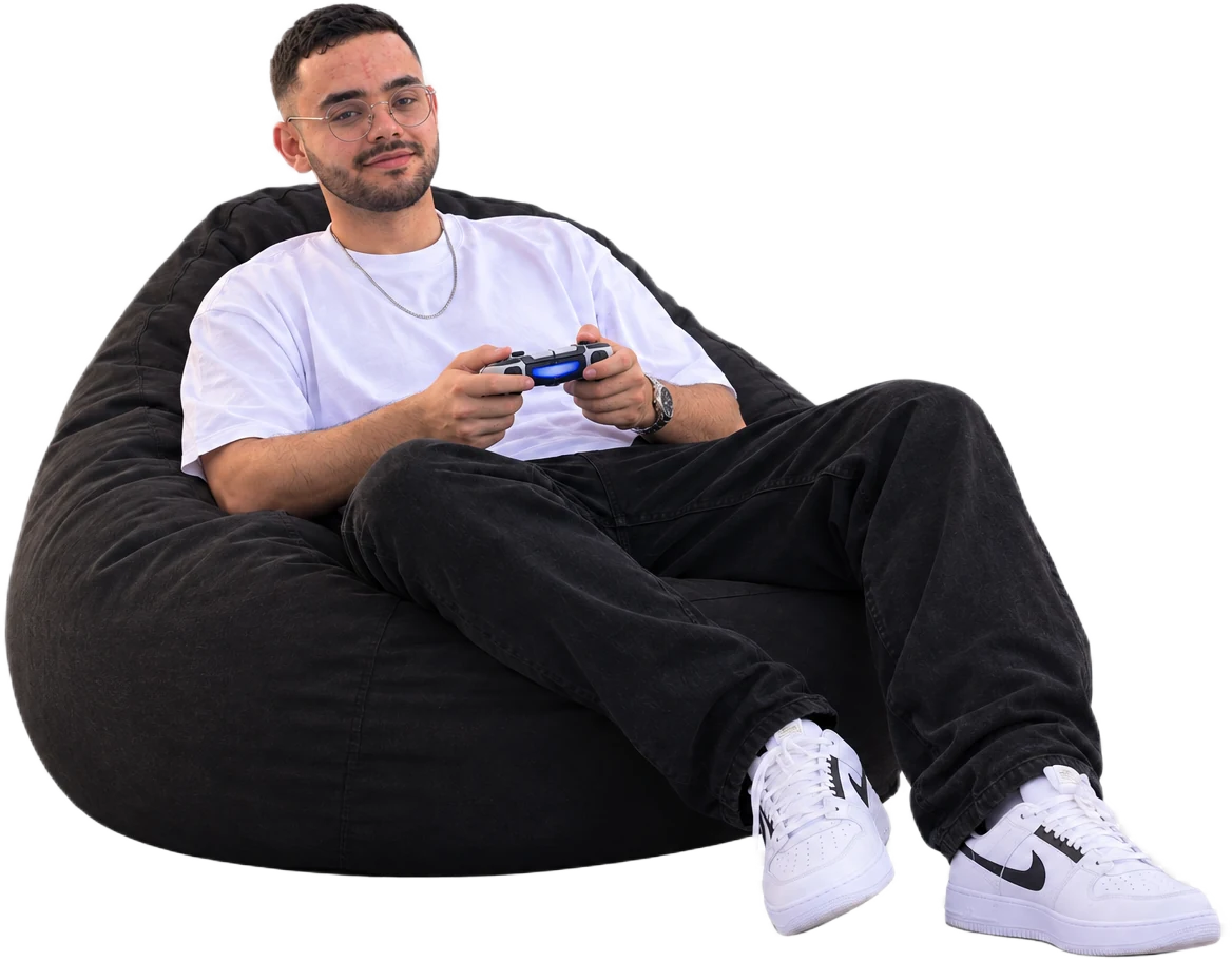 Gaya Medjedoub installé dans un pouf, une manette à la main